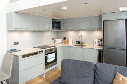 a kitchen with white cabinets and a blue couch at Kensington Arte Casa in London