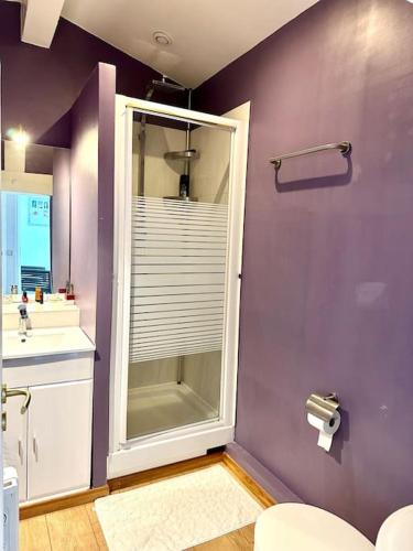 La salle de bains est pourvue de toilettes et d'un mur violet. dans l'établissement ESTEREL BELAHOME Charmant 3 pièces St Raphael Vue Mer, à Saint-Raphaël