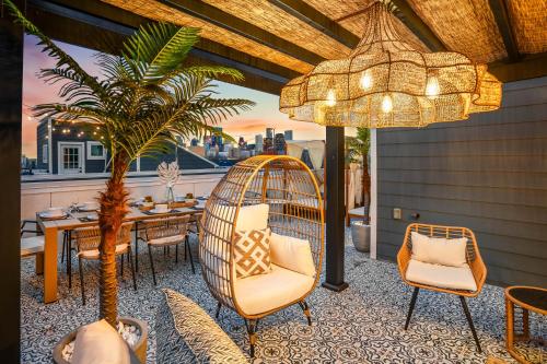 a patio with a table and chairs and a palm tree at The Green Haus: Luxxe Cabana Rooftop Retreat in Houston