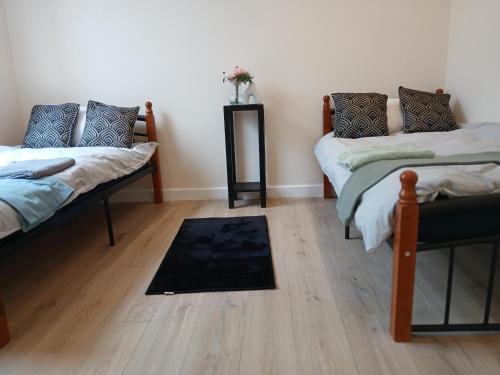 a room with two beds and a rug on the floor at Queen's Cottage in Hendon