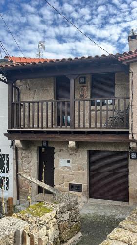 een stenen huis met een balkon en twee garagedeuren bij A MIÑA CASIÑA in Ourense