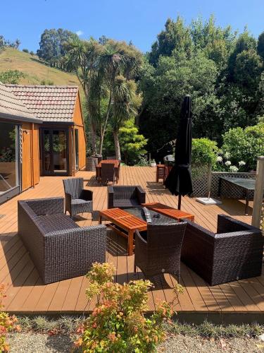 a patio with chairs and tables and an umbrella at Private Guest Wing - Durie Vale Lodge in Whanganui
