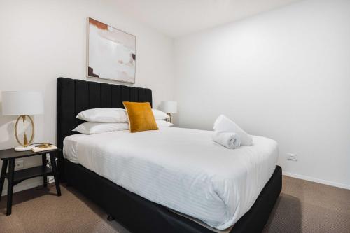 1 dormitorio con 1 cama con sábanas blancas y almohadas amarillas en Lakeside 1-Bed with Courtyard Pool Gym & Parking, en Kingston 