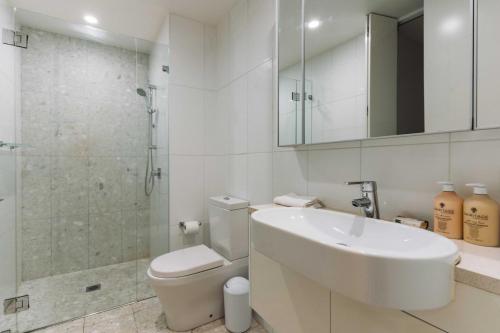 a bathroom with a sink and a toilet and a shower at Lakeside 1-Bed with Courtyard Pool Gym & Parking in Kingston 