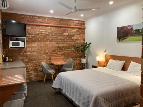 a bedroom with a bed and a brick wall at Edge Of The Forest Motel in Margaret River Town