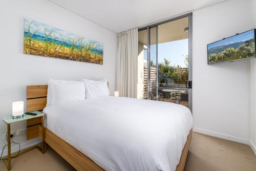 a bedroom with a white bed and a large window at Exquisite Apartment with BBQ and Pool, near Shops in Phillip