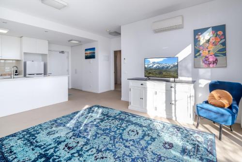 a living room with a blue rug and a kitchen at Exquisite Apartment with BBQ and Pool, near Shops in Phillip