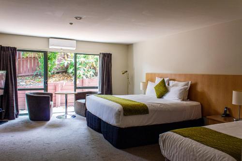 a hotel room with two beds and a balcony at Greenlane Suites in Auckland