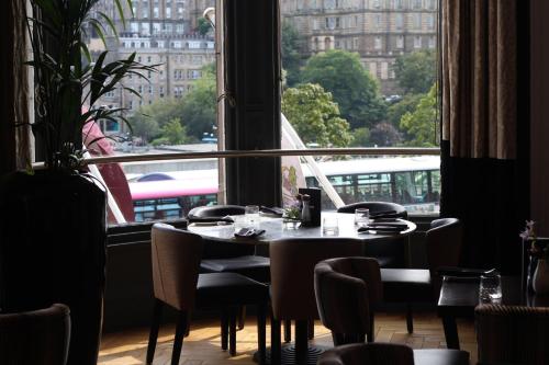 a dining room with a table and a large window at Hotel Indigo - Edinburgh - Princes Street by IHG in Edinburgh