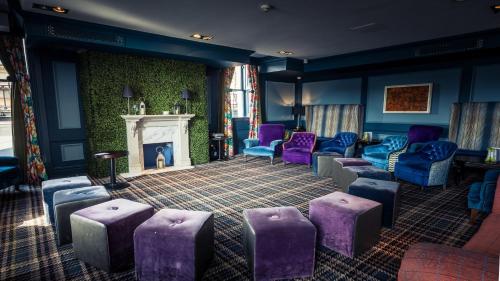 a waiting room with purple chairs and a fireplace at Hotel Indigo - Edinburgh - Princes Street by IHG in Edinburgh