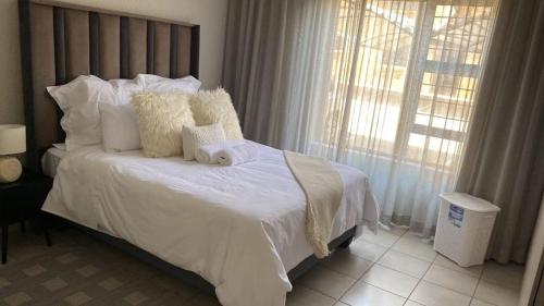a bedroom with a white bed with two teddy bears on it at Yanaz Place in Germiston