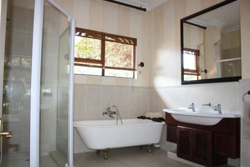 a bathroom with a tub and a sink and a mirror at 14 Zimbali Chalets in Ballito