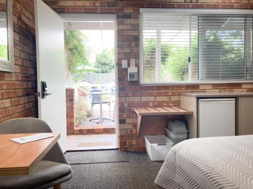 a bedroom with a bed and a brick wall at Edge Of The Forest Motel in Margaret River Town
