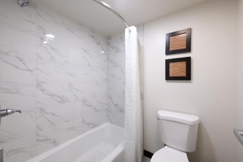 a white bathroom with a tub and a toilet at Hyland Inn near Pasadena Civic Center in Pasadena