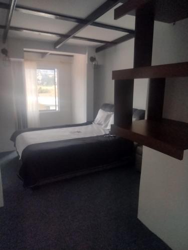 een slaapkamer met een bed en een raam bij Hotel la cava del chef in Paipa