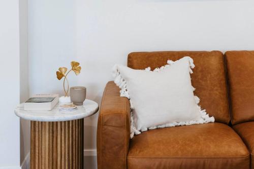 a brown couch with a white pillow next to a side table at 'Haylock' Luxe Country Charm in Mudgee's Centre in Mudgee