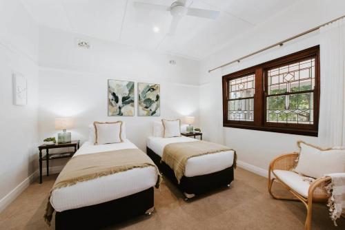a bedroom with two beds and a chair and a window at 'Haylock' Luxe Country Charm in Mudgee's Centre in Mudgee