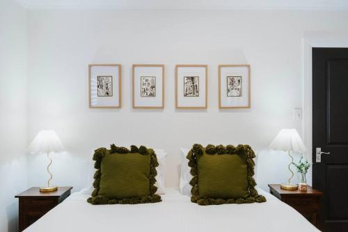 a bedroom with a white bed with two green pillows at 'Haylock' Luxe Country Charm in Mudgee's Centre in Mudgee