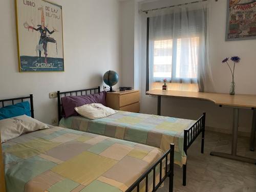 a bedroom with two beds and a desk and a table at Apartamento Guadalquivir - Parking Privado Opt in Seville