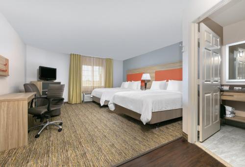 a hotel room with two beds and a television at Candlewood Suites Fort Worth West by IHG in Fort Worth