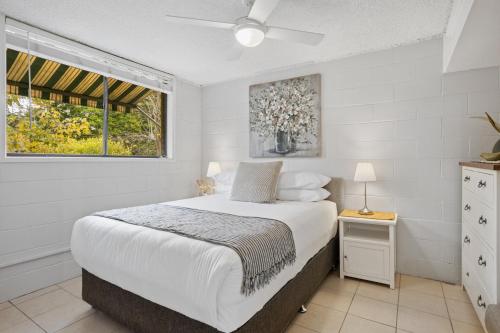 a white bedroom with a bed and a window at Inner City apartment living in quiet location in Brisbane