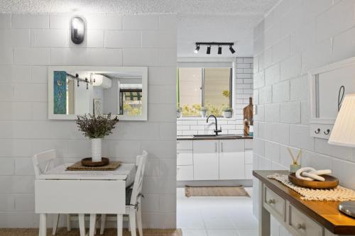 a white kitchen with a table and a sink at Inner City apartment living in quiet location in Brisbane