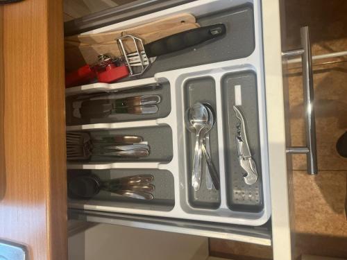 an open cabinet with silver utensils in it at Cosy Apartment in North London - Great Location in London