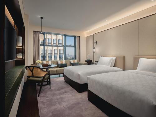 a hotel room with two beds and a couch at HUALUXE Kunshan Huaqiao by IHG - F1 Racing Preferred Hotel in Kunshan