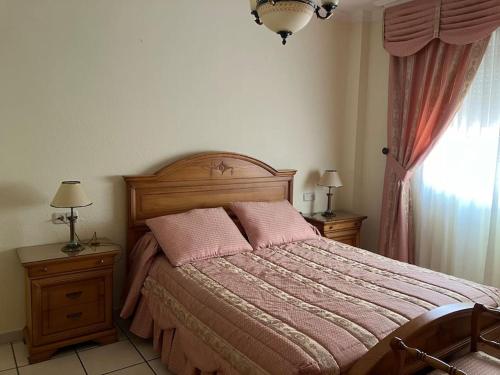 1 dormitorio con cama con sábanas rosas y ventana en Piso céntrico en Hellin, en Hellín