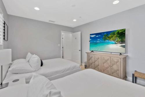 a bedroom with two beds and a flat screen tv at New cheerful villa, Pool, Spa, Mini Golf, Game room, Fire pit next to Disneyland in Anaheim