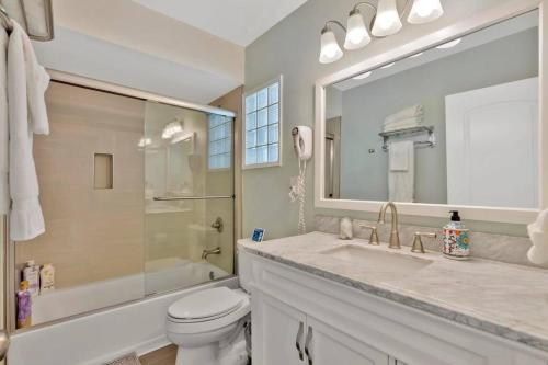 a bathroom with a sink and a toilet and a mirror at New cheerful villa, Pool, Spa, Mini Golf, Game room, Fire pit next to Disneyland in Anaheim