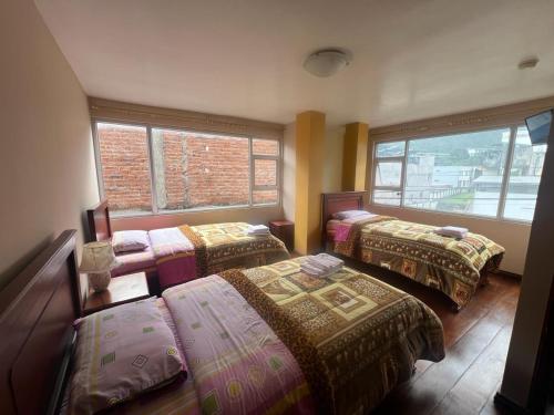Cette chambre comprend trois lits et deux fenêtres. dans l'établissement La Casa de Pia, à Baños