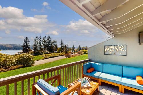 a patio with a blue couch and chairs on a balcony at Ludlow Seaside Hale' in Port Ludlow