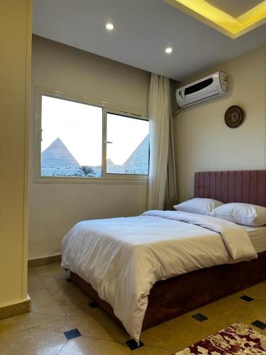 a bedroom with a large bed and a window at Pyramids Era View in Cairo