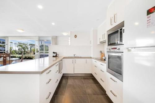a white kitchen with white cabinets and appliances at Sundeck Gardens in Maroochydore