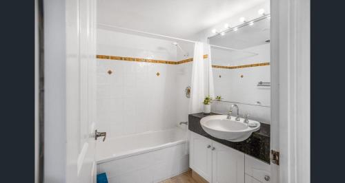 a white bathroom with a sink and a bath tub at Sundeck Gardens in Maroochydore