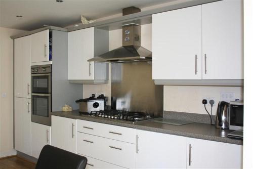 a kitchen with white cabinets and a stove top oven at Kandy Stay in Peterborough