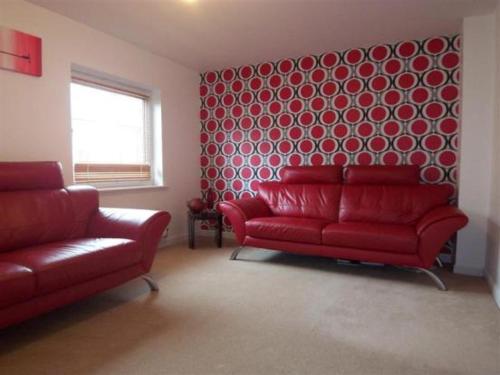 a living room with two red couches and a red wall at Kandy Stay in Peterborough