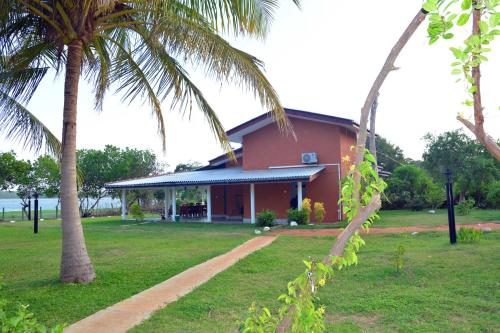 a red building with palm trees in front of it at Serenity Lake Resort Yala in Tissamaharama