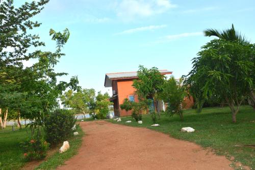a dirt road in front of a house with trees at Serenity Lake Resort Yala in Tissamaharama
