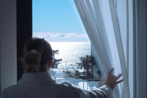 a woman looking out a window at the water at La Onda Hotel Durres in Durrës