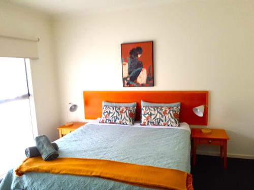 a bedroom with a large bed with a wooden headboard at 24 Gillies St Apartment in Warrnambool
