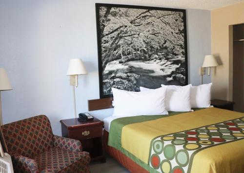 a hotel room with a bed and a chair at Super 8 by Wyndham Clarksville East in Clarksville