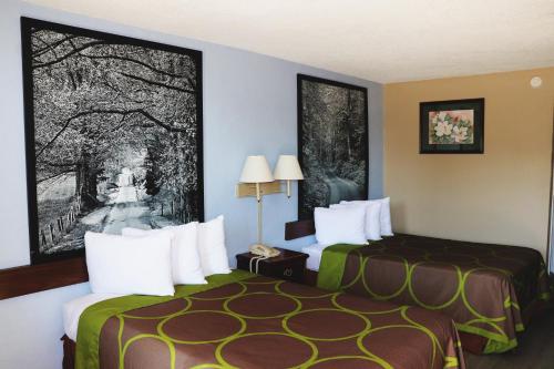 ein Hotelzimmer mit 2 Betten und einem großen Bild in der Unterkunft Super 8 by Wyndham Clarksville East in Clarksville