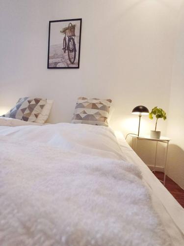 - une chambre avec un lit blanc et une photo sur le mur dans l'établissement Stylish Apartment On Pedestrian Street Randers, à Randers