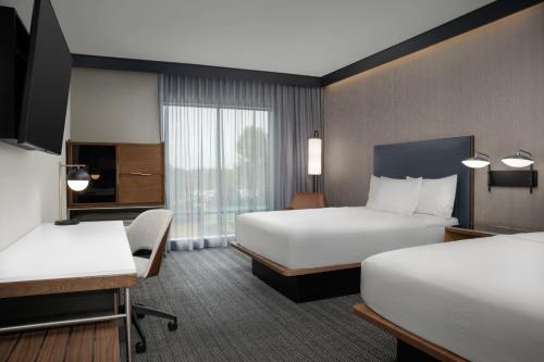 a hotel room with two beds and a television at Courtyard by Marriott Northport in Northport