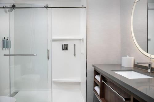 a bathroom with a glass shower and a sink at Courtyard by Marriott Northport in Northport