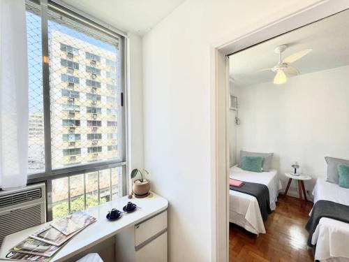 1 dormitorio con ventana, cama y espejo en Ótima localização a 2 quadras da praia!Amei en Río de Janeiro