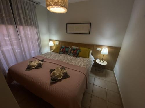 a bedroom with a bed with two flowers on it at Tejita Sun beach Holidays By Deihu Experiences in El Médano