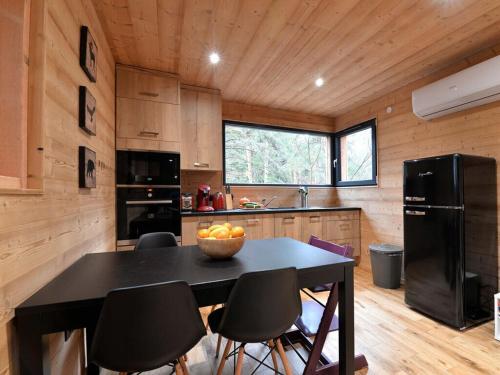 Il comprend une cuisine équipée d'une table avec des chaises et d'un réfrigérateur noir. dans l'établissement Holiday home under the trees, à Labaroche
